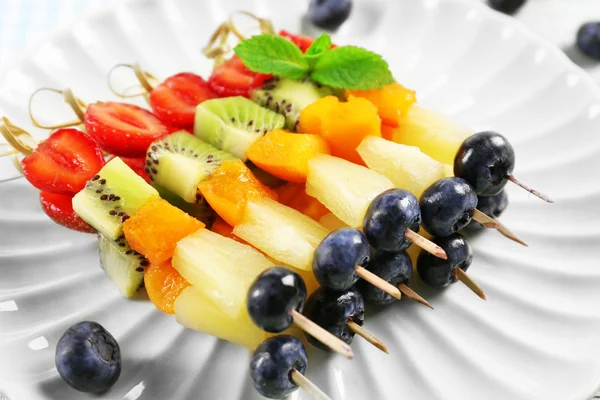 Frutas frescas en pinchos en plato sobre mesa, primer plano — Foto de Stock