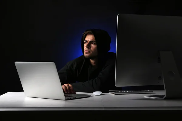 Hacker s počítačem a laptop na tmavém pozadí — Stock fotografie