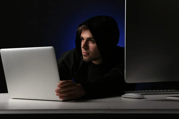 Хакер с компьютером и ноутбуком на темном фоне — стоковое фото
