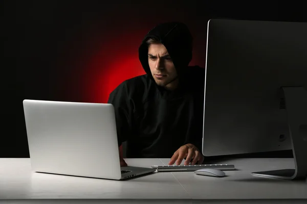 Hacker com computador e laptop no fundo escuro — Fotografia de Stock