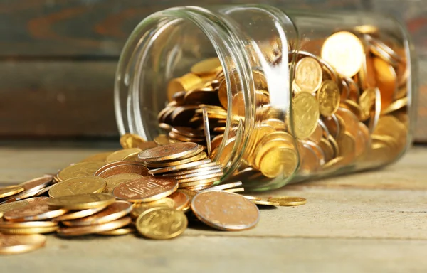 Скляна банка з монетами на дерев'яному фоні — стокове фото