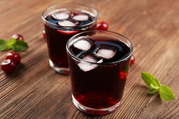 Glasses of cherry juice on wooden background — Stock Photo, Image
