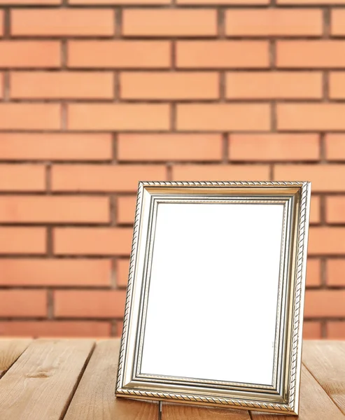 Photo frame standing on table on brick wall background — Stock Photo, Image