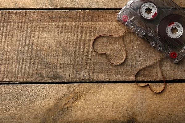 Zvuková kazeta s magnetickou páskou ve tvaru srdce na dřevěné pozadí — Stock fotografie