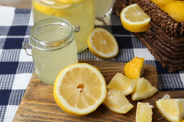 Still life with lemon juice and sliced lemons on checkered napkin, closeup — Stock Photo, Image