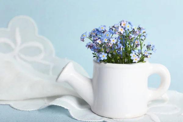 Forget-me-nots flowers in watering can, on blue background — Stock Photo, Image