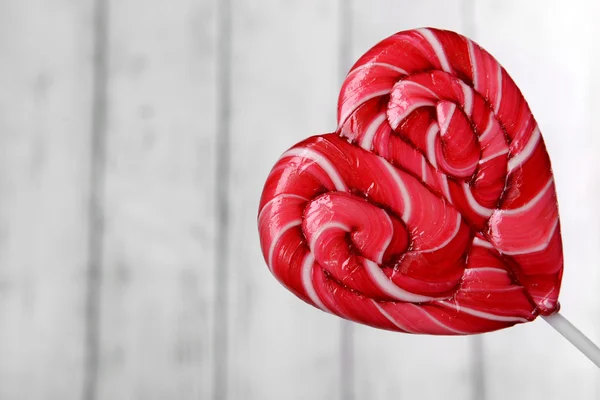 Bright lollipop in shape of heart on wooden background — Stock Photo, Image