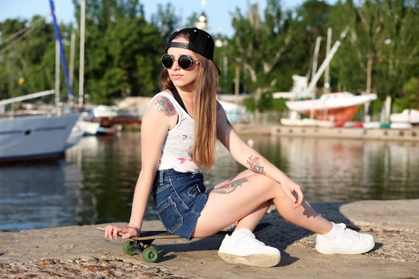 Schöne tätowierte Mädchen mit Skateboard, im Freien — Stockfoto