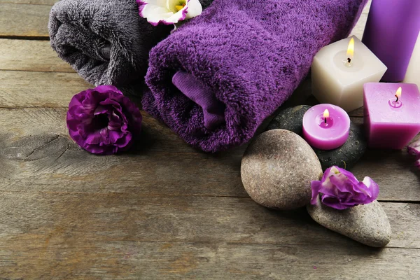 Towels, pebbles, purple flowers and candlelight — Stock Photo, Image