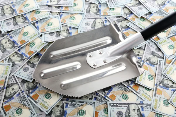 Shovel lifts dollar bills — Stock Photo, Image