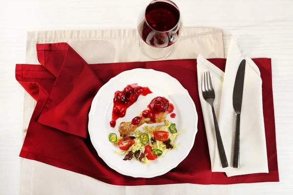 Plat de cuisse de poulet cuit au four et salade de légumes dans une assiette blanche avec verre de vin sur la table avec serviette, vue sur le dessus — Photo