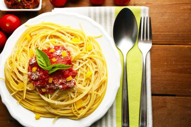 Spagetti domates sosu, kırmızı biber ve renk ahşap arka plan üzerinde beyaz plaka üzerinde peynir ile
