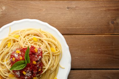Spagetti domates sosu, kırmızı biber ve renk ahşap arka plan üzerinde beyaz plaka üzerinde peynir ile