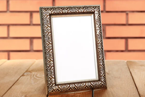 Old empty frame standing on table on brick wall background — Stock Photo, Image