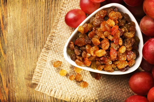 Raisins in bowl with grapes — Stock Photo, Image