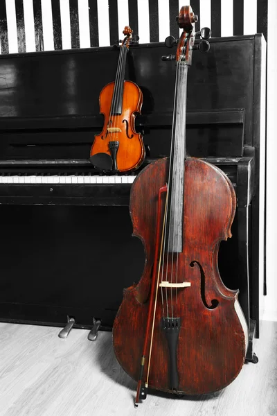 Cello and violin on piano background — Stock Photo, Image