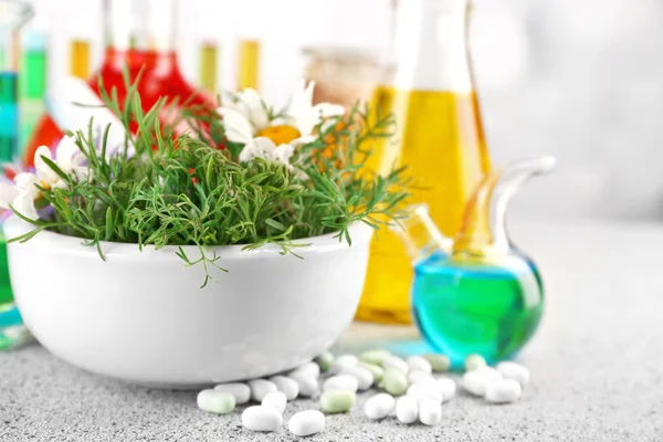 Herbs in mortar, test tubes and pills,  on table, on light background — Stock Photo, Image