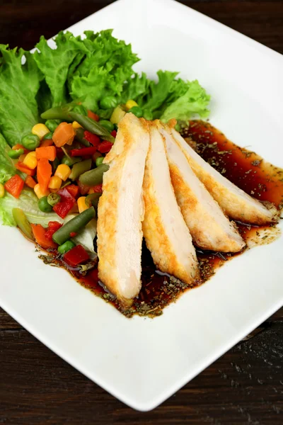 Plastry filet z kurczaka z sosem i warzywami na stole z bliska — Zdjęcie stockowe