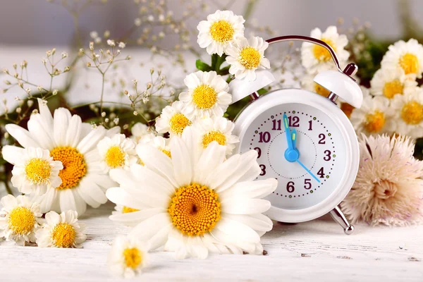 Pequeño despertador con hermosas flores —  Fotos de Stock