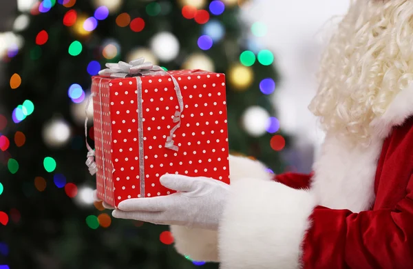 Santa celebración de regalo en el fondo del árbol de Navidad — Foto de Stock