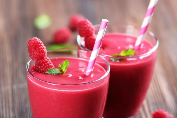 Glasses of raspberry milk shake with berries on wooden table close up — Stock Photo, Image