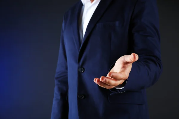 Businessman in suit introduce something on dark background — Stock Photo, Image