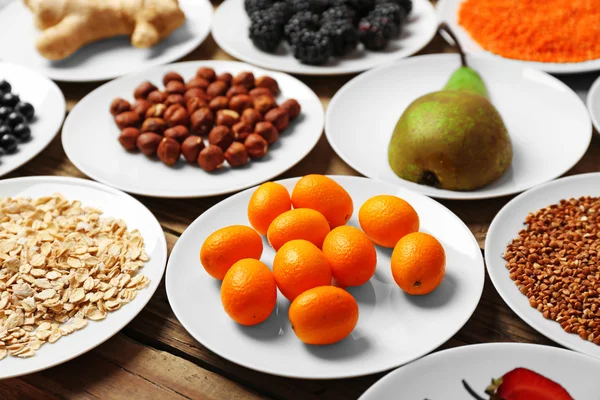 Different products on saucers on wooden table close up — Stock Photo, Image