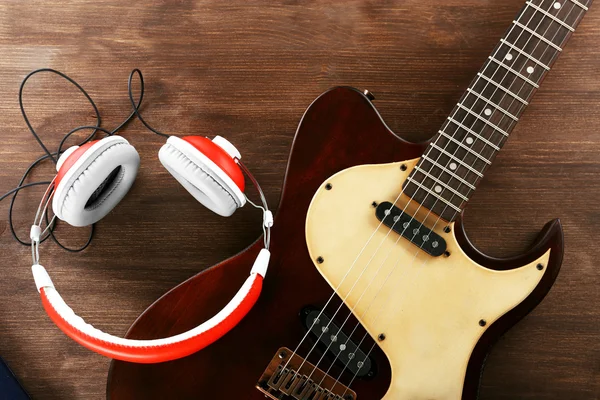 Guitarra elétrica com fones de ouvido na mesa de madeira de perto — Fotografia de Stock