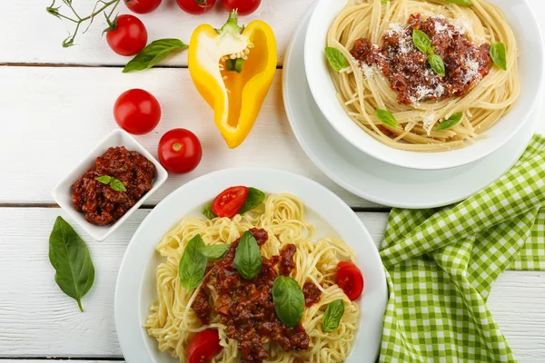 Spaghetti Bolognese auf weißem Teller, auf farbigem Holzhintergrund — Stockfoto