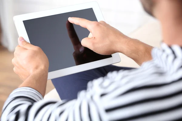 Male hand holding PC tablet on home interior background — Stock Photo, Image