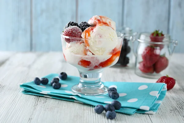 Delicioso sorvete com frutas frescas congeladas e molho, na cor de fundo de madeira — Fotografia de Stock