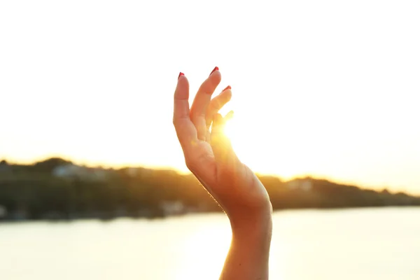 Mano femenina sobre fondo de cielo soleado — Foto de Stock