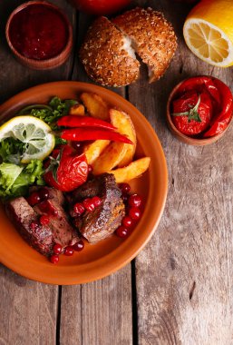 kızılcık sosu, salata ve ahşap arka plan üzerinde plaka üzerinde kavrulmuş sebze ile lezzetli kavrulmuş et