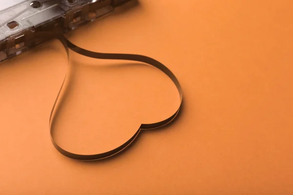 Cassette de audio con cinta magnética en forma de corazón sobre fondo naranja —  Fotos de Stock