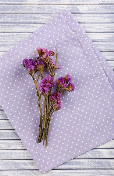 Bellissimi fiori secchi su tovagliolo su sfondo di legno — Foto Stock