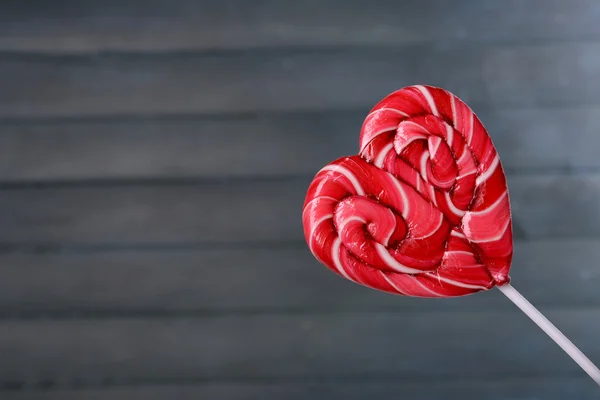 Bright lollipop in shape of heart on wooden background — Stock Photo, Image