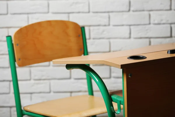 School desk and chair on white brick wall background — Stock Photo, Image