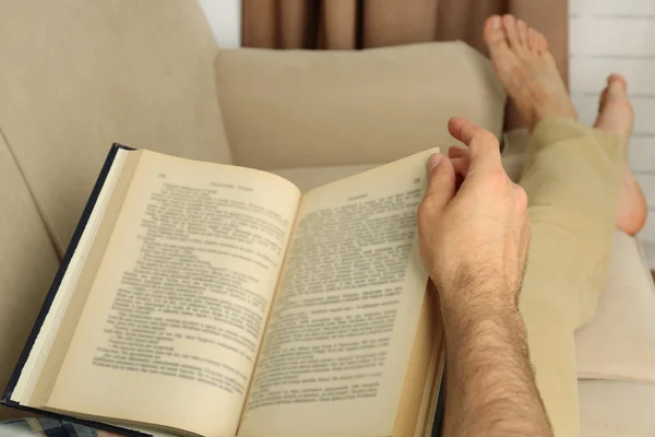 Jonge man leesboek op sofa close-up — Stockfoto