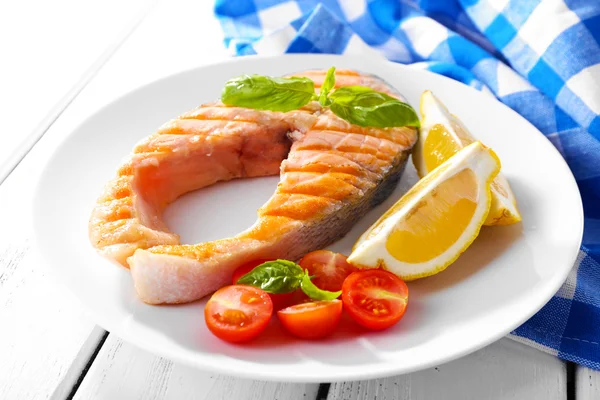 Sabroso salmón a la parrilla con tomate y limón en la mesa de cerca —  Fotos de Stock