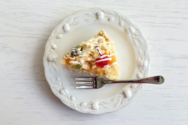 Fred av välsmakande smör tårta på plattan, färg trä bakgrund — Stockfoto