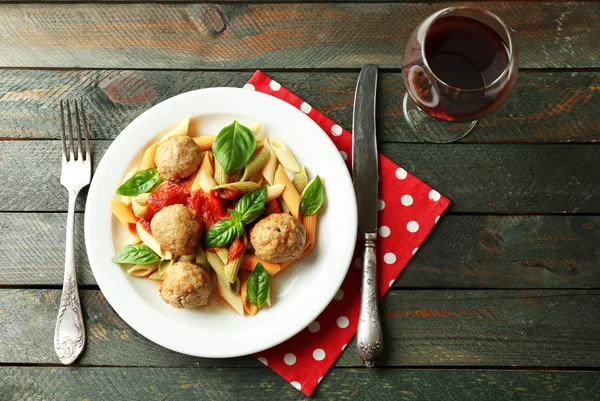 Pasta mit Frikadellen auf Teller, Glas Rotwein auf Holztischhintergrund — Stockfoto