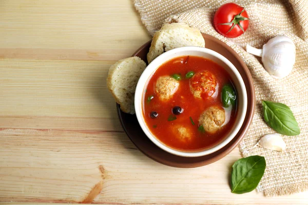 Sopa de tomate con bolas de carne sobre cuchara de madera sobre fondo de madera —  Fotos de Stock