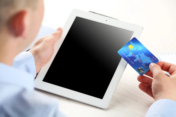 Man holding credit card and tablet on workplace background — Stock Photo, Image