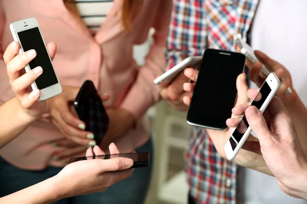 Muchas manos sosteniendo los teléfonos móviles de cerca —  Fotos de Stock