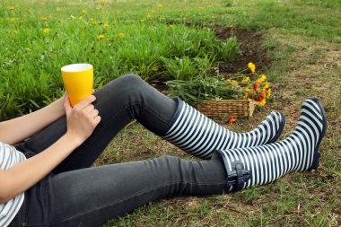 Genç kadın üzerinde çayır açık havada oturup kahve ile