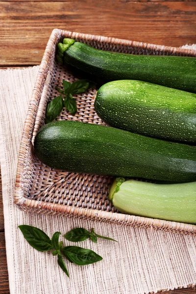 Färsk zucchini med squash och basilika på wicker bricka på nära håll — Stockfoto