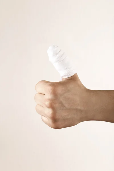 Injured bandaged finger on beige background — Stock Photo, Image