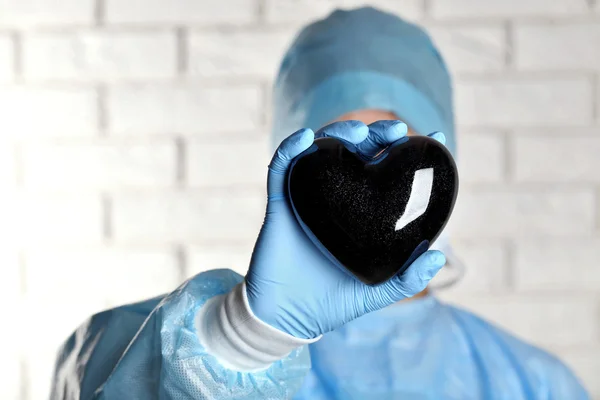 Доктор тримає декоративне серце на фоні цегляної стіни — стокове фото