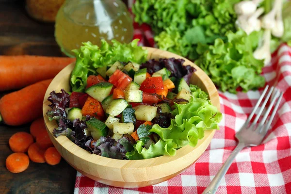 Trä skål med färska grönsaker sallad på bordet, närbild — Stockfoto