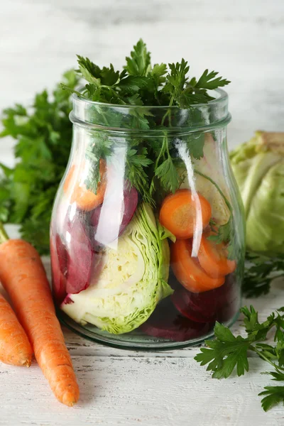 Frisches Gemüse in Glasflasche auf Holztisch, Nahaufnahme — Stockfoto